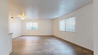 This well-organized two-bedroom, one-bathroom unit features a thoughtful single-floor layout designed for comfortable everyday living. The spacious living room is a standout feature, showcasing wood-style plank flooring, a ceiling fan, a textured ceiling, and multiple windows with vertical blinds that invite generous natural light. A second living area or dining space continues the wood-style flooring and offers a sliding glass door with views of the outdoors, further enhancing the bright, airy feel. The kitchen is efficiently laid out with white cabinetry, ample counter space, a double sink, and white appliances including a range and refrigerator, all set above warm wood-tone flooring. Both bedrooms are carpeted for comfort and feature neutral walls, ceiling vents, and good natural light. The primary bedroom is generously sized and includes a closet with a hanging rod, while the second bedroom also offers closet access. The hallway connects the rooms seamlessly, leading to the full bathroom which features a clean white tub-shower combination with tiled surround and chrome fixtures. A dedicated closet provides additional storage. Overall, the unit presents a clean, neutral palette with consistent finishes throughout.