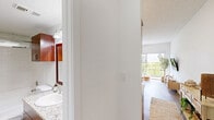 Located in Miami, FL, this thoughtfully designed one-bedroom, one-bathroom residence offers a well-utilized, compact footprint across a single floor. The open-concept living area flows seamlessly into the kitchen, which features rich cherry wood cabinetry, granite countertops, stainless steel appliances, and a breakfast bar with seating — ideal for casual dining. Hardwood-style flooring runs throughout the space, lending warmth and visual continuity.

The spacious bedroom is a standout feature, accommodating a ceiling fan, a wall-mounted TV, a built-in open shelving unit, and a large sliding glass door that fills the room with natural light while offering direct views of lush greenery outside. A dedicated closet provides organized storage within the bedroom area.

The bathroom is clean and functional, featuring warm cherry wood cabinetry, a granite-topped vanity with a vessel sink, and a full tub-shower combination. Textured ceilings and neutral wall tones carry throughout the home, creating a bright and cohesive aesthetic. Ceiling fans in key areas enhance air circulation, a practical comfort in Miami's warm climate. Overall, this residence delivers a functional and inviting living environment with notable attention to detail.