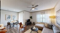 Located at 3700 Preston Rd in Plano, TX, this one-bedroom, one-bathroom residence offers a well-designed single-level layout that makes smart use of its compact footprint. The open-concept living and dining area is anchored by wood-style flooring, crown molding, and a ceiling fan with integrated lighting. Natural light streams in through large windows dressed with sheer curtains and vertical blinds, creating a bright and welcoming atmosphere. The dining space sits adjacent to sliding glass doors, adding an airy feel to the area.

The kitchen is outfitted with white shaker cabinetry, light quartz countertops, a subway tile backsplash, and a full suite of stainless steel appliances including a refrigerator, range, and microwave. A peninsula with a built-in sink provides additional prep space and casual seating.

The bedroom features plush carpeting, a ceiling fan, and a well-sized window that brings in natural light. A dedicated closet and a connecting hallway add to the unit's functional layout. The bathroom includes a tiled tub-shower combo with a curved curtain rod, brushed nickel fixtures, and classic white tile detailing. A hallway provides access to an in-unit washer and dryer, completing this thoughtfully arranged residence.