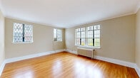 This well-designed 2-bedroom, 1-bathroom residence showcases a blend of classic architectural character and functional living across a single floor. The living room is a standout space, featuring warm hardwood floors, elegant crown molding, and a generous arrangement of leaded diamond-pane windows that flood the room with natural light and lend a distinctive period charm. A cast-iron radiator adds to the vintage character while providing efficient heating.

The kitchen is laid out in a practical galley style, offering ample warm-toned wood cabinetry, laminate countertops, tile flooring, and white appliances including a refrigerator and range — providing efficient use of space for cooking and storage.

Both bedrooms are carpeted and well-proportioned, each featuring crown molding and cast-iron radiators. The primary bedroom benefits from multiple windows with natural light, while the second bedroom includes a built-in closet with louvered bifold doors. A connecting hallway links the rooms with ease.

The bathroom is a true architectural highlight, finished floor-to-ceiling in vintage green ceramic tile with warm grout tones. A classic pedestal sink, soaking tub, wall sconce lighting, and a leaded glass window complete this distinctly elegant space. Throughout the residence, consistent detailing and thoughtful finishes create a cohesive and timeless atmosphere.