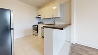Located at 1592 Bathurst St in Toronto's midtown neighbourhood, this 2-bedroom, 1-bathroom unit offers a clean, functional layout across a single floor. The interior features a consistent palette of white walls and light wood laminate flooring throughout the main living and bedroom areas, creating a bright and cohesive aesthetic.

The kitchen is finished with white cabinetry, a tile backsplash, dark countertops, and a peninsula that separates it from the adjoining living area. Stainless steel appliances, including a refrigerator and electric range, are included. Light tile flooring runs through the kitchen area.

A central hallway connects the main living spaces and leads to both bedrooms and the bathroom. The primary bedroom is generously sized and features a large window with views of the surrounding Toronto cityscape, a radiator heating unit, and light wood flooring. The second bedroom is more compact but equally well-lit, with its own window offering outdoor views and matching flooring.

The bathroom is finished with white subway-style wall tiles and includes a full soaker tub with a small window above for natural light. A dedicated hallway closet provides additional storage. The unit's clean, neutral finishes and natural light throughout make it a practical and comfortable urban residence.