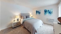 Located at 20430 Leapwood Ave in Carson, California, this single-story unit offers a well-organized layout designed for comfortable everyday living. The living area is anchored by a large sliding glass door fitted with vertical blinds, opening directly onto a private outdoor patio furnished with seating — an ideal extension of the interior living space, with views of surrounding palm trees and neighboring architecture.

The kitchen is equipped with white cabinetry, a coil-burner electric range, a full-size refrigerator, and tile countertops, providing a functional cooking environment. Adjacent to the kitchen, the dining area features wood-style flooring, a ceiling fan with light fixture, and a mirrored wall that enhances the sense of depth in the space.

Two bedrooms offer plush carpeting and neutral walls, creating a quiet, restful atmosphere. One bedroom includes a wide dresser with a framed mirror. The primary bathroom presents an extended vanity with warm stone-toned countertops, white cabinetry, vessel sinks, and a large mirror. A second full bathroom includes a shower-tub combination with a curtain and wood-style flooring throughout. The overall aesthetic is clean, neutral, and move-in ready.