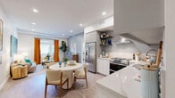 Located at 10375 Washington Blvd in Los Angeles, CA, this thoughtfully designed 2-bedroom, 2-bathroom residence offers a well-organized single-level layout. The open-concept kitchen and living area serves as the heart of the home, featuring light wood-style flooring, recessed lighting, and bright white walls that create a clean, contemporary atmosphere. The kitchen is equipped with stainless steel appliances including a double-oven range, a French door refrigerator, a dishwasher, and a wall-mounted range hood. White cabinetry is complemented by quartz countertops and open floating shelves, adding both function and style. A dining area adjoins the kitchen, flowing seamlessly into the living room, which features large windows dressed with bold orange curtains that let in generous natural light. The primary bedroom includes a tray ceiling with integrated ambient lighting, a large window with views to the exterior, and a dedicated closet. The second bedroom, also with a tray ceiling, offers a versatile layout suitable as a home office or guest room. Both bathrooms feature a modern floating vanity with dark countertops, large-format tile flooring, and illuminated mirrors. One bathroom includes a spacious glass-enclosed walk-in shower with floor-to-ceiling tile surround.