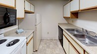 Located at 9237 Greenback Ln in Orangevale, California, this single-floor unit offers a practical and comfortable layout across several well-defined spaces. The galley-style kitchen is efficiently designed with ample upper and lower cabinetry featuring wood-trimmed white doors, laminate countertops, a stainless steel sink, a dishwasher, a full-size refrigerator, and tile flooring that adds durability to a high-use area. The living area is generously proportioned, featuring soft carpeting and a sliding glass door that welcomes natural light and provides outdoor access. The bedrooms are comfortably sized, each with plush carpet flooring and windows that bring in natural light. One bedroom includes a ceiling fan with light fixture and closet storage, while the primary bedroom features a walk-in closet with built-in shelving and a full-length mirrored sliding door. Two full bathrooms serve the unit, each equipped with a tub and shower combination, a toilet, a vanity with storage, and tile flooring. The overall layout is straightforward and functional, with neutral tones throughout that provide a clean, versatile canvas well-suited to a variety of living arrangements.