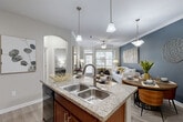 Located at 24929 Katy Ranch Rd in Katy, TX, this single-story, one-bedroom, one-bathroom residence offers a thoughtfully designed open-concept layout that maximizes its comfortable footprint. The kitchen is a standout feature, showcasing rich warm-toned cabinetry, granite countertops, black appliances including a range, microwave, and refrigerator, and a central island with a double sink and bar seating — ideal for both cooking and casual dining. Track lighting and pendant lights illuminate the space stylishly. The kitchen flows seamlessly into the combined dining area and living room, where light wood-style flooring, crown molding, and a ceiling fan contribute to an inviting atmosphere. The living room is anchored by a bold accent wall and large windows that bring in generous natural light. The bedroom features plush carpeting, a ceiling fan, ample closet space, and a bright window with outdoor views, creating a calm and restful retreat. The bathroom is finished with matching warm-toned cabinetry, a white vanity countertop, and a shower-tub combination. Additional highlights include a dedicated laundry area, three closets for generous storage, an entrance foyer, a hallway, and a private patio — rounding out this efficiently designed and well-finished home.