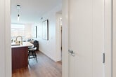 Located at 707 South Worth Street in Birmingham, Michigan, this thoughtfully designed one-bedroom, one-bathroom residence offers a sleek, modern aesthetic throughout its efficiently arranged single-floor layout. Warm hardwood flooring flows seamlessly across all living areas, anchoring the contemporary design palette.

The open-concept kitchen and living area serves as the heart of the home. The kitchen is outfitted with high-gloss upper cabinetry in a warm taupe finish, complemented by wood-toned lower cabinets, crisp white countertops, a clean tile backsplash, and a full suite of stainless steel appliances including a french door refrigerator, built-in microwave, and range. A peninsula with bar seating connects the kitchen to the dining area, making entertaining effortless.

The living room is bright and airy, featuring floor-to-ceiling windows and a glass door that open to outdoor views of the Birmingham cityscape, flooding the space with natural light. The spacious primary bedroom continues the floor-to-ceiling window theme, offering generous natural light and outdoor views.

The walk-in closet is exceptionally well-appointed with dual hanging rods on either side and a central shelving unit, providing ample organized storage. The bathroom features a large, elegantly tiled walk-in shower with a bench, dual showerheads, and refined brushed nickel fixtures, delivering a spa-like experience.