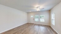 Located at 335 Marigold Drive in Myrtle Beach, SC, this two-story home offers four bedrooms, two bathrooms, and a well-designed layout spread across two floors. The main floor serves as the heart of the home, anchored by an open-concept kitchen and living area. The kitchen is appointed with gray shaker-style cabinetry, white quartz countertops, a large center island with pendant lighting, and a full suite of stainless steel appliances including a range, microwave, dishwasher, and French door refrigerator. Light wood-look flooring flows throughout the main living areas, enhancing the bright, clean aesthetic. Bedrooms feature a mix of wood-look flooring and plush carpeting, with ceiling fans and natural light from well-placed windows. The bathrooms are finished with gray vanity cabinetry and white quartz countertops. A dedicated laundry room houses a full-size washer and dryer with overhead shelving for added convenience. The attached garage provides additional storage and parking. Outside, the property boasts a generous, open backyard with lush green grass and a mature wooded tree line, offering a sense of privacy and natural tranquility in a coastal South Carolina setting.
