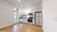 Located at 4520 Charlotte Park Dr in Charlotte, NC, this single-floor residence offers a clean, modern aesthetic defined by an open-concept layout and warm hardwood-style flooring that flows seamlessly throughout the space. The kitchen is a functional centerpiece, outfitted with white shaker cabinetry, granite countertops, a classic subway tile backsplash, and a full suite of stainless steel appliances including a refrigerator, electric range, microwave, and dishwasher. A pendant track light fixture adds a contemporary touch overhead. Large windows and a glass door flood the kitchen and adjoining living area with abundant natural light, offering pleasant outdoor views and a bright, airy atmosphere. The living area is generously proportioned, featuring a ceiling fan, large windows with blinds, and crisp white walls that enhance the sense of openness. The bathroom is well-appointed with a granite-topped vanity with white cabinetry, a full soaking tub and shower combo, and consistent hardwood-style flooring that ties the space together. The overall design emphasizes clean lines, neutral tones, and practical finishes, making this a comfortable and move-in-ready residence in the Charlotte area.