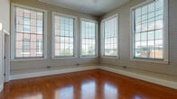 Located at 89 Globe Mills Ave in Fall River, Massachusetts, this single-floor unit blends classic mill building character with modern interior finishes. The open living area is a standout, showcasing rich hardwood flooring that runs throughout and impressively tall ceilings that lend a sense of expansive volume. Structural columns add architectural interest while defining the transition between the living space and the kitchen.

The kitchen is well-equipped, featuring warm honey-toned cabinetry, granite countertops, and a full suite of stainless steel appliances, including a refrigerator, range, built-in microwave, and dishwasher. Track lighting overhead ensures practical illumination. The living and dining areas open naturally from the kitchen, creating a cohesive, functional layout.

The bedroom offers plush carpeting, large windows that invite natural light and neighborhood views, and the convenience of dual closets providing generous storage. A second carpeted room with corner windows offers flexibility as an additional bedroom or office.

The bathroom is finished with a granite-topped vanity, tile flooring, and a full tub-shower combination. Throughout the unit, large multi-pane windows frame views of the surrounding area, filling each room with natural light and reinforcing the building's historic mill aesthetic.