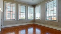 Located at 89 Globe Mills Ave in Fall River, Massachusetts, this single-floor unit blends classic mill building character with modern interior finishes. The open living area is a standout, showcasing rich hardwood flooring that runs throughout and impressively tall ceilings that lend a sense of expansive volume. Structural columns add architectural interest while defining the transition between the living space and the kitchen.

The kitchen is well-equipped, featuring warm honey-toned cabinetry, granite countertops, and a full suite of stainless steel appliances, including a refrigerator, range, built-in microwave, and dishwasher. Track lighting overhead ensures practical illumination. The living and dining areas open naturally from the kitchen, creating a cohesive, functional layout.

The bedroom offers plush carpeting, large windows that invite natural light and neighborhood views, and the convenience of dual closets providing generous storage. A second carpeted room with corner windows offers flexibility as an additional bedroom or office.

The bathroom is finished with a granite-topped vanity, tile flooring, and a full tub-shower combination. Throughout the unit, large multi-pane windows frame views of the surrounding area, filling each room with natural light and reinforcing the building's historic mill aesthetic.