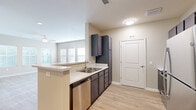 Located in Charleston's historic 29403 zip code, this well-appointed one-bedroom, one-bathroom residence offers a thoughtfully designed open-concept layout with modern finishes throughout. The combined kitchen and living area serves as the heart of the home, featuring light wood-look flooring, a ceiling fan, and a wall of windows fitted with white blinds that flood the space with natural light. The kitchen is equipped with dark espresso cabinetry, stainless steel appliances including a refrigerator, range, microwave, and dishwasher, complemented by clean white countertops and a peninsula that provides additional prep space and casual seating. The spacious bedroom is carpeted for comfort and includes dual windows, a ceiling fan, and ample wall space. The full bathroom features wood-look flooring, a dark-toned vanity, a full tub-shower combination, and a clean, neutral palette. A dedicated laundry room with washer/dryer hookups and wire shelving adds everyday convenience. A closet provides additional storage. Neutral warm-toned walls throughout create a cohesive, move-in-ready atmosphere suited to a variety of furnishing styles.