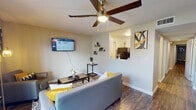 Located at 722 W Carolina St in Tallahassee, FL, this single-story unit presents a well-organized layout with a consistent design aesthetic throughout. Wood-look flooring runs through the majority of the space, complemented by neutral-toned walls and white trim that create a clean, cohesive look.

The living area serves as the heart of the unit, featuring a ceiling fan with integrated lighting and a sliding glass door that opens to an outdoor patio, allowing natural light to flow in and providing outdoor views. A pass-through opening connects the living area to the kitchen, which is equipped with black appliances including a refrigerator, electric range, and over-the-range microwave, alongside cabinetry with granite-style countertops and a pantry closet for additional storage.

A long hallway with recessed lighting connects the various rooms, including a carpeted bedroom, a bathroom with granite-style countertops and white cabinetry, and two dedicated office rooms. Each office benefits from natural light through windows with blinds and ceiling fans. The bathroom features a full vanity with a large mirror. The layout is practical and efficiently organized, making it a versatile space suitable for both living and working.