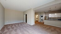 Located at 1250 Ewing St in Fort Wayne, Indiana, this single-floor unit offers a well-designed layout that maximizes functionality within a compact footprint. The open-concept living and kitchen area creates a seamless flow between spaces, with plush patterned carpeting covering the generous living room, which is bathed in natural light from a large sliding glass door fitted with vertical blinds.

The kitchen is a standout feature, outfitted with crisp white cabinetry, dark granite countertops, and stainless steel appliances including a refrigerator, range, and microwave. A peninsula with a built-in sink and pendant lighting above serves as both a prep area and casual dining space, while hardwood-style flooring grounds the kitchen zone with warmth and contrast.

The bathroom continues the consistent design aesthetic, featuring a white vanity with granite countertop, a large mirror, and hardwood-style flooring. A glass-enclosed shower completes the space.

Practical amenities include a dedicated walk-in closet and a conveniently located stacked washer and dryer unit. Neutral warm-gray tones throughout the unit create a cohesive and inviting ambiance. The entry door is solid and secure, opening into the living area for a welcoming arrival experience.