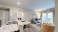 Located at 7405 Long Lake Rd in Columbus, OH, this 4-bedroom, 2-bathroom single-floor residence offers a thoughtfully designed layout with a neutral, contemporary aesthetic throughout. The open-concept kitchen and living area serves as the heart of the home, featuring rich dark cabinetry, light granite-style countertops, black appliances, and a peninsula with bar seating — ideal for casual dining or entertaining. A dedicated closet off the kitchen provides convenient pantry storage. Wood-style flooring extends through the main living areas, transitioning to plush carpet in the living room and bedrooms. The living room is bright and welcoming, with access to a private outdoor area through sliding glass doors fitted with vertical blinds. The four bedrooms offer comfortable, carpeted retreats with warm neutral tones; the primary bedroom includes a closet and natural light from a window. Both bathrooms are well-appointed — one features a walk-in glass shower with a dark vanity and granite countertop, while the second includes a shower-tub combination. A hallway connects the bedroom wing to the main living areas, creating a clear and practical flow throughout the home.