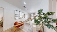 Located in Washington, Utah, this thoughtfully designed two-bedroom, two-bathroom unit offers efficient, single-floor living with a clean, contemporary aesthetic. The open-concept kitchen is a standout feature, showcasing two-tone cabinetry with deep green lower cabinets and crisp white uppers, white quartz countertops, stainless steel appliances, open shelving, and a center island with bar seating illuminated by modern pendant lighting. Light wood-look flooring flows throughout the main living areas, adding warmth and continuity. The living room features large windows that invite natural light, complemented by neutral tones and a welcoming, airy atmosphere. Both bedrooms are carpeted for comfort and include windows with blinds and drapes, providing ample natural light and privacy. The primary bedroom offers a well-proportioned layout with a dedicated closet. Each bathroom mirrors the kitchen's design language, featuring green vanity cabinetry, white quartz countertops, large mirrors, and tub-shower combinations with light wood-look flooring. Clean white walls and modern fixtures are consistent throughout. The overall design balances modern style with functional living, making this a well-appointed and move-in-ready home.