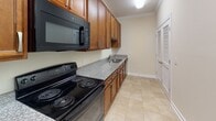 Located at 1100 Palisades Cir in Asheville, NC, this single-floor residence offers a well-appointed layout with consistent, quality finishes throughout. The kitchen is efficiently designed with warm honey-toned wood cabinetry, speckled granite countertops, a double stainless steel sink, and black GE appliances including a range, microwave, and dishwasher. Light ceramic tile flooring and louvered bi-fold doors add functional character to the space. The main living and dining areas feature soft carpeting, crown molding, and an elegant chandelier in the dining space, while the living room is equipped with a ceiling fan and a large window that brings in natural light. Additional rooms continue the warm, neutral color palette with plush carpet, white panel doors, and ample natural light from well-placed windows. The bathroom is clean and practical, offering a granite-topped vanity with wood cabinetry, a tub-shower combination, and tile flooring matching the kitchen. Throughout the residence, consistent crown molding, neutral beige walls, and thoughtful lighting fixtures contribute to a cohesive and comfortable interior aesthetic well-suited to the Asheville setting.