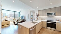 This thoughtfully designed 2-bedroom, 2-bathroom residence delivers a clean, contemporary aesthetic throughout its single-floor layout. A bright hallway with recessed lighting and warm hardwood flooring serves as the central artery, connecting all rooms seamlessly. The open-concept kitchen and living area is a standout feature, showcasing light wood cabinetry, quartz countertops, a large center island with an undermount sink, and a full suite of stainless steel appliances. Floor-to-ceiling windows in the living and dining area flood the space with natural light and frame sweeping city views. The primary bedroom is a serene retreat, featuring a large window with urban vistas, a ceiling fan, and access to a walk-in closet with built-in shelving and hardwood flooring. The two bathrooms are finished with floating wood-tone vanities, quartz countertops, and light tile floors, conveying a spa-like calm. A dedicated office provides a quiet, functional workspace with open shelving. Additional highlights include a second closet, a laundry room, and consistent hardwood flooring throughout the living areas, all contributing to a polished and cohesive urban living experience.