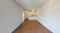 Located at 8503 Tobias Ave in the Panorama City neighborhood of Los Angeles, this single-floor unit offers a clean, functional layout ideal for comfortable everyday living. The main living area is expansive and open, featuring warm wood-look laminate flooring and a textured ceiling with a ceiling light fixture, creating a bright and welcoming atmosphere. A pass-through opening connects the living space to the galley-style kitchen, which is equipped with a gas range, double-basin sink, laminate countertops, and ample white cabinetry above and below — providing efficient use of the available space. The bedroom is carpeted for comfort and includes a wall-mounted air conditioning unit and a window that brings in natural light. The full bathroom offers a generous vanity with white cabinetry and a large mirror, wood-look flooring, and a shower-tub combination with a curtain enclosure. Additional storage is accessible via a closet visible from the bathroom area. Throughout the unit, the neutral white walls and consistent flooring choices contribute to a cohesive, light-filled interior that is easy to personalize and maintain.