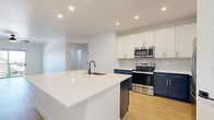 Located at 18220 N 68th St in Phoenix, AZ, this single-story, 3-bedroom, 2-bathroom home offers a thoughtfully designed layout with modern finishes throughout. The open-concept kitchen and living area serves as the heart of the home, showcasing a striking two-tone cabinet design with crisp white upper cabinets and deep navy lower cabinets, accented by gold hardware. A large center island with a white quartz countertop and undermount sink provides ample prep space, while stainless steel appliances, including a French door refrigerator, electric range, and built-in microwave, complete the chef-friendly kitchen. A geometric tile backsplash adds a decorative touch. Light wood-look flooring flows consistently throughout the home, complementing the clean, neutral color palette. The bedrooms are well-proportioned and bright, each featuring ceiling fans and natural light from windows or sliding glass doors that offer outdoor views. The primary bedroom includes access to a walk-in closet and a private bathroom with navy cabinetry, a white quartz vanity, and a tiled tub-shower combination. A dedicated laundry room with washer and dryer hookups adds everyday convenience. Recessed lighting and modern panel-style interior doors complete the home's contemporary aesthetic.