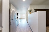Located at 2065 South Cherokee Street in Denver, CO, this thoughtfully designed one-bedroom, one-bathroom unit offers a smart and functional layout on a single floor. Light wood-style flooring runs throughout, creating a cohesive and bright aesthetic across every room.

The kitchen is a standout feature, outfitted with stainless steel appliances including a full-size refrigerator, stove, and microwave. Two-tone cabinetry — with upper white shaker cabinets and lower gray cabinets — pairs with butcher block-style countertops and a subway tile backsplash for a clean, modern look. The galley-style layout maximizes efficiency and storage.

The living area is open and airy, bathed in natural light from a forward-facing window. Built-in open shelving adds practical storage and character to the space without overwhelming it.

The bathroom continues the modern design language, featuring a vanity with gray cabinetry, a wood-tone countertop, and a vessel sink. Conveniently, an in-unit stacked washer and dryer is located adjacent to the bathroom, adding a practical amenity rarely found in comparably sized units.

Two closets provide additional storage throughout the unit. The overall design is clean, contemporary, and well-appointed, making efficient use of every square foot.