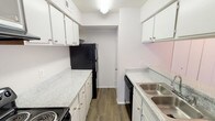 Located at 2775 N Collins St in Arlington, Texas, this single-story unit offers a practical and comfortable layout across several well-defined living spaces. The galley-style kitchen is equipped with white cabinetry, speckled laminate countertops, a stainless steel sink, and black appliances including a refrigerator, dishwasher, and range. Wood-look vinyl flooring runs throughout the kitchen, complementing the clean, neutral color palette. A doorway at the end of the kitchen leads further into the unit.

The living room is a bright, open space featuring a white wood-burning fireplace as a central focal point, flanked by two windows dressed with horizontal blinds that allow ample natural light. Plush carpet and a textured ceiling complete the relaxed atmosphere of this gathering area.

The bedrooms are carpeted and offer a calm, neutral environment. One bedroom features crown molding, built-in shelving, and a ceiling light fixture, while another includes a ceiling fan with light and a window with an outdoor view. Both bedrooms include closets with bifold doors for storage.

Two full bathrooms each include a tub-shower combination with white tile surround and chrome fixtures. One bathroom features wood-look flooring, while the other offers a more traditional finish. The overall design is clean and functional throughout.