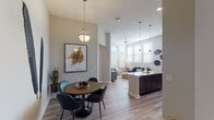 Located on Millenia Lakes Boulevard in Orlando, Florida, this single-floor residence offers a thoughtfully designed open-concept layout with contemporary finishes and abundant natural light throughout. The living and dining areas flow seamlessly together, anchored by light wood-style flooring, elevated ceilings, and large windows that invite generous sunlight into the space. A stylish pendant light and artistic wall décor accent the dining nook, which comfortably accommodates a round table and seating. The kitchen is a standout feature, showcasing rich dark cabinetry, stainless steel appliances including a range, microwave, and refrigerator, and a generous granite-topped island with bar seating. Pendant lighting above the island adds warmth and visual interest. The living area benefits from soaring ceilings and transom windows, enhancing the sense of openness. The bedrooms are carpeted and well-proportioned, with large windows offering ample natural light and ceiling fans for comfort. The bathrooms are cleanly finished, featuring wood-toned vanities with white quartz countertops, framed mirrors, and wood-look flooring. The primary bathroom includes a glass-enclosed tiled shower, while a secondary bath provides a single vanity with refined detailing. Overall, the space presents a cohesive modern aesthetic with warm, neutral tones and upscale finishes.