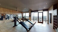 Located at 351 S Jackson St in Denver's sought-after Cherry Creek neighborhood, this fitness center offers a thoughtfully designed workout environment that combines functionality with refined aesthetics. The single-level space is finished with light hardwood flooring throughout, complemented by warm wood-paneled accent walls that lend a contemporary yet welcoming atmosphere.

The workout area is well-appointed with a variety of exercise equipment, including incline trainers, functional training machines, and a comprehensive multi-rack storage system stocked with kettlebells, medicine balls, stability balls, and TRX suspension trainers. Full-length mirrors line one wall, enhancing the sense of openness while providing visual feedback during workouts.

Natural light floods the space through large, floor-to-ceiling windows and glass doors that open to an outdoor terrace, offering panoramic views of the Denver skyline and surrounding neighborhood. The terrace extends the usable space and provides an outdoor setting for stretching or cool-down activities.

Recessed lighting and ceiling fans are integrated throughout, ensuring a comfortable environment during any workout. The overall design balances clean, modern lines with natural materials, creating a fitness space that is both practical and visually appealing.