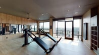 Located at 351 S Jackson St in Denver's sought-after Cherry Creek neighborhood, this fitness center offers a thoughtfully designed workout environment that combines functionality with refined aesthetics. The single-level space is finished with light hardwood flooring throughout, complemented by warm wood-paneled accent walls that lend a contemporary yet welcoming atmosphere.

The workout area is well-appointed with a variety of exercise equipment, including incline trainers, functional training machines, and a comprehensive multi-rack storage system stocked with kettlebells, medicine balls, stability balls, and TRX suspension trainers. Full-length mirrors line one wall, enhancing the sense of openness while providing visual feedback during workouts.

Natural light floods the space through large, floor-to-ceiling windows and glass doors that open to an outdoor terrace, offering panoramic views of the Denver skyline and surrounding neighborhood. The terrace extends the usable space and provides an outdoor setting for stretching or cool-down activities.

Recessed lighting and ceiling fans are integrated throughout, ensuring a comfortable environment during any workout. The overall design balances clean, modern lines with natural materials, creating a fitness space that is both practical and visually appealing.