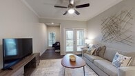 This well-appointed single-story residence showcases a thoughtfully designed open-concept layout with dark hardwood-style flooring and neutral gray walls that create a cohesive, contemporary aesthetic throughout.

The kitchen serves as a central highlight, featuring dark espresso cabinetry, granite countertops, a subway tile backsplash, and stainless steel appliances including a range, microwave, and dishwasher. A kitchen island with pendant lighting provides additional prep space and casual seating, while open shelving and a built-in wine rack add functional character.

The living room benefits from multiple windows and French doors that invite natural light and provide outdoor access. Crown molding and a ceiling fan with light fixture enhance the room's polished feel. A separate dining nook accommodates a four-seat table and features additional storage closets nearby.

The primary bedroom includes a ceiling fan, direct access to an en suite bathroom with dark cabinetry and a well-lit vanity mirror, and a walk-in closet. The second bedroom also features a ceiling fan and its own walk-in closet. The bathroom offers a tub-shower combination with clean white finishes and dark wood-tone cabinetry with granite countertops, maintaining the design consistency found throughout the residence.