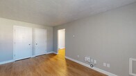 Located at 4301 S 6th St in Terre Haute, Indiana, this 2-bedroom, 1-bathroom unit offers a compact and efficiently designed single-floor layout. Light-toned vinyl plank flooring runs throughout the space, providing a clean and cohesive look that ties each room together.

The living area greets residents at the front entry, featuring neutral gray walls, a textured ceiling, and a window with natural light along with a wall-unit air conditioner. Baseboard heating is present throughout, offering consistent warmth across all rooms.

The kitchen is a standout feature, showcasing white cabinetry with matte black hardware, granite-style countertops, and black appliances including an electric range with an overhead ventilation hood. The galley-style layout makes efficient use of the available space.

The primary bedroom is generously sized, offering two closet doors and a textured ceiling, while the second bedroom includes a window with outdoor views and its own baseboard heater. Both rooms maintain the same neutral palette and vinyl flooring found throughout the unit.

The bathroom is clean and functional, equipped with a full tub and shower combo, a single-sink vanity with white cabinetry, a mirror, and a towel ring — all finished in bright white for a crisp, tidy appearance.