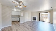 Located in Arden-Arcade, CA, this 2-bedroom, 2-bathroom unit is thoughtfully laid out across a single floor. The open-concept living, dining, and kitchen area serves as the heart of the home, featuring light hardwood-style flooring, a ceiling fan, and a white-brick fireplace with glass doors. Sliding glass doors lead directly to a private balcony, filling the living space with natural light and outdoor views. The kitchen is well-appointed with white cabinetry extending to the ceiling, granite-style countertops, a stainless sink, and black appliances including a refrigerator, range, and dishwasher. Both bedrooms are carpeted and receive natural light through large windows with vertical blinds. The primary bedroom includes a built-in closet with shelving, while the second bedroom is served by a spacious walk-in closet with dual hanging rods. The bathrooms feature hardwood-style flooring, white vanities, and granite-style countertops. A utility room and hallway round out the floor plan. The exterior showcases a wood-sided multi-unit building surrounded by mature trees, with staircase access and a landscaped common area.