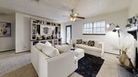 Located at 7302 University Row in San Antonio, TX, this 2-bedroom, 2-bathroom residence offers a well-organized single-floor layout with a cohesive modern design throughout. The living room serves as the heart of the home, featuring a striking black-tiled fireplace with a display mantel, plush carpeting, a ceiling fan, and large windows that invite natural light. An open built-in shelving unit adds both style and function to the space.

The kitchen is appointed with dark navy cabinetry accented by gold hardware, granite-look countertops, a white subway tile backsplash, and black appliances including a range, refrigerator, and over-the-range microwave. Light wood-look flooring ties the space together and extends into the bathrooms.

Both bedrooms are carpeted and equipped with ceiling fans and windows. The primary bedroom is generously sized, offering a dedicated closet and direct access to an en-suite bathroom. The second bedroom also features a closet and window for natural light. Each bathroom is finished with dark upper cabinetry with gold hardware, a tub-shower combination, and light wood-look flooring. Two closets provide ample storage throughout the residence.
