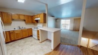 Located at 1315 Villa Park Cir in Bellevue, WI, this single-floor unit offers a practical and well-organized layout designed for comfortable everyday living. The kitchen is a functional highlight, featuring warm oak cabinetry with ample upper and lower storage, white appliances including a refrigerator, electric range, and under-cabinet range hood, along with a double sink and light tile flooring. A peninsula counter connects the kitchen to the adjacent living area, creating an open and communicative flow between spaces. The living room is generously sized with plush carpeting, a baseboard heating system, and a sliding glass door that brings in natural light and provides outdoor access. Bedrooms are carpeted and well-proportioned, each equipped with ceiling fans and access to closet space. One bedroom notably includes convenient in-unit washer and dryer access, adding a practical touch to the private quarters. A built-in wall shelf adds a functional architectural detail to one of the rooms. The bathroom features a wide vanity with oak cabinetry, a large mirror, tile flooring, and a shower-tub combination. Throughout the unit, warm wood trim accents doorways and baseboards, lending a cohesive and inviting aesthetic to the overall space.