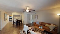 Located at 2136 Lobdell Blvd in Baton Rouge, Louisiana, this single-story residence offers a well-organized layout with consistent wood-look flooring and a neutral color palette throughout. The open living area provides a comfortable and functional space, featuring a textured ceiling, ceiling fan with light fixture, and windows fitted with blinds that allow natural light to filter in. The living room flows seamlessly into the dining area, which accommodates a full dining set and connects visually to both the kitchen and an in-unit laundry area. The kitchen is outfitted with warm wood cabinetry, granite-style countertops, a stainless steel refrigerator, and a range, offering practical functionality. Bedrooms are adequately sized, each equipped with ceiling fans, wood-look flooring, and windows that bring in natural light. One bedroom is notably versatile, with two windows and ample wall space. The bathroom features a full tub-shower combination with beige tile surround accented by a decorative mosaic border, wood cabinetry with a granite-style vanity top, and wood-look flooring, presenting a clean and cohesive finish. An in-unit washer and dryer hookup area adds everyday convenience to this practical Baton Rouge residence.