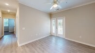 Located at 6725 N Main St in Columbia, SC, this well-appointed single-floor home offers three bedrooms, two bathrooms, and a thoughtfully designed layout. The kitchen is a standout feature, showcasing gray shaker-style cabinetry, stone-look countertops, stainless steel appliances including a refrigerator, electric range, and built-in microwave, along with a peninsula with an integrated sink and light wood-style flooring that flows throughout the main living areas. The living area benefits from natural light and provides access to an outdoor space through double French doors, complemented by crown molding and a ceiling fan overhead. The bedrooms are finished with plush carpet and ceiling fans, offering a comfortable retreat. Each bedroom includes double closet doors providing ample storage, and windows that invite natural light and outdoor views. The primary bedroom is generously sized with its own closet access. The two bathrooms are finished with light wood-style flooring, gray vanity cabinetry, and clean white fixtures. One bathroom features a full tub and shower combination, while the second offers a vanity with a mirror and a toilet. Neutral warm-toned walls throughout create a cohesive and inviting atmosphere across the entire home.