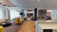 Located at 1720 Oak Ave in Evanston, Illinois, this single-floor amenity space offers a sophisticated, multi-zone layout designed for both social gatherings and relaxed everyday use. The open floor plan seamlessly connects several distinct areas, each with its own character while maintaining a cohesive contemporary aesthetic throughout.

Herringbone hardwood flooring anchors the main circulation areas, transitioning into patterned carpet in the dining zones. The dining areas feature a variety of seating configurations, including communal tables, intimate two-tops with marble surfaces, and banquette-style booths, all illuminated by recessed lighting and a striking sculptural globe chandelier. Floor-to-ceiling sheer curtains line the perimeter windows, flooding the space with abundant natural light and framing views of the tree-lined streetscape outside.

A built-in modern fireplace with sleek tile surround serves as a warm focal point in the lounge area, complemented by bold velvet accent chairs in mustard yellow and rich jewel tones. A cozy lounge nook features an oversized wall-mounted Scrabble board, adding a playful, residential touch.

The full catering kitchen is equipped with stainless steel appliances, dark wood cabinetry, and a white countertop island with plush bar seating. A separate wet bar area with pendant lighting and mosaic tile backsplash completes the entertainment offerings, making this an exceptionally well-appointed communal space.