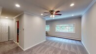 Located at 427 Main Street in Northport, NY, this single-floor residence at Fairfield Northport Village offers a well-organized layout with thoughtfully finished interiors throughout. The main living area is generously proportioned, featuring plush wall-to-wall carpeting, soft gray walls, and crown molding that adds a refined architectural detail. Recessed lighting and a ceiling fan with an integrated light fixture provide both ambient illumination and air circulation, while a bank of windows along the far wall invites natural light and frames views of the surrounding greenery.

The kitchen is efficiently designed with warm wood cabinetry, dark granite countertops, tile flooring, and full appliances including a refrigerator. A doorway from the kitchen leads to a carpeted area with a closet, offering additional storage. The bedroom is a comfortable, well-lit space with carpeting, crown molding, a ceiling fan, a window overlooking lush outdoor foliage, and a wall-mounted HVAC unit. The bathroom features a tub-shower combination enclosed by a sliding glass door, white tile surround with accent detailing, and a vanity with dark granite countertop. Throughout, the unit maintains a clean, neutral aesthetic with consistent finishes.