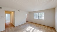 Located at 2700 Boulevard Rd in Elsmere, Delaware, this single-floor, one-bedroom, one-bathroom unit offers a well-organized layout with a practical mix of rooms and generous storage options. The living room is bright and welcoming, featuring neutral carpet flooring and multiple windows dressed with blinds that invite natural light and views of surrounding greenery. The space flows naturally toward the entry door, creating an open and airy feel throughout. The kitchen is outfitted with warm oak cabinetry extending to the upper walls, light countertops, a stainless steel sink, a full-size refrigerator, and a dishwasher, along with an adjacent pantry for additional storage. A hallway connects the main living areas to the private bedroom, which is a generously sized retreat featuring plush carpeting, a large double-door closet, and a window with outdoor views. The bathroom is clean and functional, with wood-look tile flooring, a warm oak vanity with under-cabinet storage, a mirrored medicine cabinet, and white subway tile accents lining the shower and walls. Additional closets and a dedicated utility room provide exceptional storage capacity throughout. Louvered closet doors and consistent neutral tones contribute to the unit's cohesive, practical aesthetic.