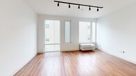 Located at 4240 Chestnut Street in Philadelphia's University City neighborhood, this one-bedroom, one-bathroom unit offers a thoughtfully designed layout across a single floor. Warm hardwood-style flooring runs throughout the entire space, creating a cohesive and inviting feel.

The open-plan kitchen and living area form the heart of the unit. The kitchen is equipped with stainless steel appliances—including a refrigerator, gas range, dishwasher, and built-in microwave—complemented by white cabinetry extending to the ceiling for ample storage and a clean, modern aesthetic. A sliding barn door adds a stylish architectural touch to the space. The living area benefits from large windows that allow natural light to fill the room, with an in-unit PTAC climate control unit ensuring year-round comfort.

The bedroom is a cozy, well-proportioned retreat featuring a built-in closet with bi-fold doors, providing practical storage. The bathroom is clean and modern, offering a walk-in shower, a vanity with a gray countertop, and light wood cabinetry. Black track lighting runs throughout the main living areas, providing flexible, directed illumination. The overall design is contemporary and minimalist, making efficient use of every square foot.