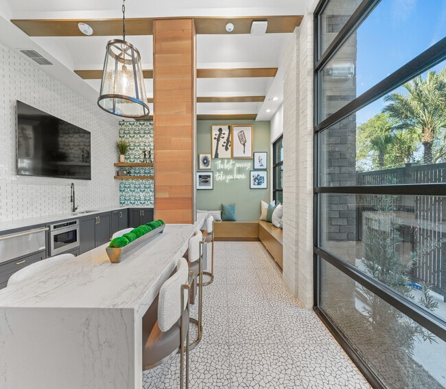 Cocina moderna y elegante con una isla con estilo, iluminación elegante y una acogedora zona de estar con una vista panorámica a través de una gran ventana. - Elan Crown Point