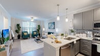 This single-floor residence is thoughtfully designed with a seamless open-concept layout that connects the entryway, kitchen, and living area into one cohesive, light-filled space. The entryway welcomes residents with light wood-tone flooring, crown molding, and ample wall space, setting an inviting tone throughout.

The kitchen is a standout feature, outfitted with gray shaker-style cabinetry, a mosaic tile backsplash, white quartz countertops, a large center island with a stainless steel sink, and a full suite of stainless steel appliances including a refrigerator, range, microwave, and dishwasher. Pendant lighting over the island adds a refined touch.

The open living area is generously proportioned, featuring crown molding, a ceiling fan, and large windows dressed with sheer curtains and blinds that invite abundant natural light. A dedicated nook serves as a functional home office space with neutral tones and ample wall space for personalization.

The bedroom is a serene retreat with soft carpeting, a large window offering natural light, and direct access to a well-designed full bathroom. The bathroom features light wood-tone flooring, a full tub-shower combination, and white arched-panel doors leading to closet storage. Throughout, the design palette of soft whites, warm neutrals, and light wood tones creates a calm, modern ambiance.