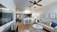 Located at 4649 Loma del Sur Dr in El Paso, TX, this one-bedroom, one-bathroom residence offers a thoughtfully designed single-floor layout that maximizes every square foot. The open-concept living and dining area is bright and welcoming, featuring warm hardwood-style flooring, vaulted ceilings, and a ceiling fan overhead. Large windows allow natural light to fill the space, while the front entry area offers a cozy reading nook with views to the outdoors. The living room flows seamlessly into the combined dining and kitchen area, anchored by a breakfast bar with seating — ideal for casual dining or entertaining. The galley-style kitchen is well-equipped, featuring warm wood cabinetry, granite-style countertops, a double sink, and black appliances including a refrigerator, range, and dishwasher. The bedroom is a comfortable retreat finished with plush carpet, a ceiling fan, a natural-light window, and access to two closets for ample storage. The full bathroom includes a wood-toned vanity with granite countertops, a framed mirror, and a tub/shower combination. A dedicated laundry area and a hallway complete the functional floor plan, making this a practical and comfortable home.