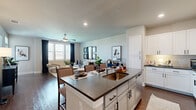 This two-story home is thoughtfully designed to maximize both functionality and style. The main living level hosts the majority of the space, beginning with an open-concept kitchen and living room that serves as the heart of the home. The kitchen features white shaker cabinetry with dark hardware, stainless steel appliances, and a large center island with a dark quartz countertop and built-in sink — ideal for both meal preparation and casual dining. The living area flows seamlessly from the kitchen, offering rich dark hardwood flooring, recessed lighting, a ceiling fan, and large windows that invite abundant natural light. The bedroom is a comfortable retreat with plush carpeting, a ceiling fan, and generous windows. The full bathroom is finished with white cabinetry, dark countertops, and direct access to a well-organized walk-in closet with built-in shelving. A dedicated laundry room includes a full-size washer and dryer. The ground floor provides a private garage with interior access via staircase. Neutral tones and consistent finishes throughout create a cohesive, modern aesthetic from top to bottom.