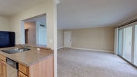 This single-story unit in Florida offers a practical, well-organized layout designed for comfortable everyday living. The open-concept living area is generously proportioned, featuring neutral-toned carpet, clean white baseboards, and crown molding details that add a refined touch. A central entry door anchors the main living space, which flows seamlessly toward the kitchen via a pass-through counter with granite-style laminate surfaces and warm wood cabinetry.

The kitchen is thoughtfully equipped with ample upper and lower cabinetry, a built-in wine rack, a gas range, refrigerator, and tile flooring in a classic diagonal pattern. A peninsula counter doubles as a casual dining or workspace area, enhancing functionality.

The bedrooms are carpeted and bathed in natural light through horizontal-blind-fitted windows with outdoor views. Each room provides a calm, neutral palette with sufficient space for standard furnishings. A spacious walk-in closet with wrap-around hanging rods offers generous storage.

Two full bathrooms feature tub-shower combinations with full tile surrounds, brushed nickel fixtures, and diagonal tile flooring, providing a cohesive and clean aesthetic throughout the unit.