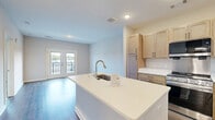 Located at 3260 Clifton Springs Rd in Decatur, GA, this well-appointed one-bedroom, two-bathroom residence offers a thoughtfully designed single-floor layout. The open-concept kitchen and living area serves as the heart of the home, featuring light maple cabinetry, stainless steel appliances including a gas range, over-the-range microwave, and refrigerator, complemented by a central island with a white countertop and sink — ideal for both cooking and casual dining. Rich hardwood-style flooring flows throughout the main living spaces, adding warmth and continuity. The living room is bright and welcoming, highlighted by a set of French doors that open to a private balcony offering pleasant outdoor views. The generously sized bedroom is finished with plush carpet, a ceiling fan, and a window that allows natural light to fill the space. Two full bathrooms provide added convenience, with one featuring a soaking tub, light wood vanity cabinetry, and clean white finishes. A dedicated laundry area with washer and dryer hookups adds everyday practicality. Throughout the residence, neutral tones and modern detailing create a clean, contemporary ambiance suited for comfortable living.