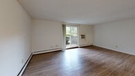 Located at 38 Cedar Pond Dr in Warwick, Rhode Island, this single-floor, one-bedroom, two-bathroom residence offers a functional and comfortable layout with generous living space. Hardwood-style flooring runs throughout, lending a clean, cohesive look to every room.

The kitchen features a U-shaped configuration with rich, dark wood cabinetry, white countertops, and full appliances including a dishwasher, electric range, and refrigerator. A pantry provides additional storage, and the adjoining hallway leads into the dining area, accented by a classic chandelier.

The spacious living room receives natural light through a large sliding glass door that opens onto a private balcony with greenery views, while a wall-mounted A/C unit ensures year-round comfort. The bedroom is generously sized with its own closet and easy hallway access. Four closets throughout the unit offer abundant storage.

Both bathrooms feature tub-shower combinations with tiled surrounds — one with white subway tile and yellow accent tile, and the other with classic blue tile and a vanity with mirror. Textured ceilings and baseboard heating complete the interior details. The overall layout is practical and well-organized, making efficient use of every square foot.