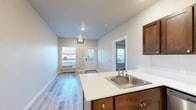 Located at 821 N Stanley St in Medical Lake, WA, this one-bedroom, one-bathroom unit offers a well-designed single-level layout that maximizes every square foot. Light-toned luxury vinyl plank flooring runs throughout the entire space, creating a cohesive and easy-to-maintain aesthetic.

The open-concept kitchen serves as the functional heart of the unit, featuring rich dark walnut-toned cabinetry, white countertops, a stainless steel sink, and a full suite of stainless steel appliances including a refrigerator, electric range, and over-the-range microwave. A peninsula with bar seating connects the kitchen to the living area, enhancing the open flow and providing additional workspace.

The living area is bright and welcoming, with recessed lighting, a wall-mounted HVAC unit, and a windowed entry door that allows natural light to fill the space. The bedroom is a comfortable, well-proportioned room with a window offering natural light and views to the exterior.

The bathroom is thoughtfully appointed with a wide vanity mirror, dark wood cabinetry, white countertops, a single-basin sink, and a full shower-tub combo. Clean, neutral wall tones throughout the unit contribute to a fresh and modern ambiance, making the space move-in ready.