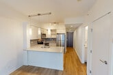 Located at 805 14 Avenue SW in Calgary's vibrant Beltline neighbourhood, this efficiently designed one-bedroom, one-bathroom unit offers a thoughtful layout across a single floor. Light hardwood flooring runs throughout the main living areas, complementing the clean, contemporary aesthetic defined by crisp white walls and recessed lighting.

The open-concept kitchen is a standout feature, equipped with full stainless steel appliances including a refrigerator, electric range, and built-in microwave. White cabinetry with ample storage reaches toward the ceiling, while a grey subway tile backsplash adds a modern accent. A peninsula with a light stone countertop and undermount sink provides both workspace and a natural division between the kitchen and the living area, which is brightened by a large window with city views.

The bedroom is a well-proportioned, bright space with large windows overlooking the Calgary skyline, light hardwood floors, and a built-in nook ideal for storage or a wardrobe. The full bathroom features large-format grey floor tiles, a combined tub and shower with clean white tile surround, a wide vanity with an undermount sink, and a large mirror.

Additional conveniences include three closets and a dedicated in-unit laundry space housing a stacked washer and dryer.