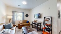 Located at 15 Tri-Park Way in Appleton, Wisconsin, this single-floor, 4-bedroom, 2-bathroom unit is thoughtfully designed for shared living. The open-plan layout connects the kitchen and living area seamlessly, with wood-look flooring and a pendant light anchoring the space. The kitchen is well-appointed with dark walnut cabinetry, gray countertops, a full suite of black appliances including a range, microwave, dishwasher, and refrigerator, and ample upper and lower cabinet storage. The living area beyond offers a comfortable, inviting atmosphere with natural light from a large window. Each of the four bedrooms features plush carpet flooring, a window with blinds and curtains for natural light and privacy, and space for a bed and desk — functional layouts well-suited for studying and rest. The primary bedroom is notably more spacious, while additional bedrooms offer a cozy, efficient use of space. One bedroom includes a built-in shelf and hanging rod for storage. The two bathrooms are finished with wood-look vinyl flooring, warm walnut vanity cabinetry, undermount sinks with modern fixtures, and well-lit mirrors. A hallway and closet complete the unit, providing connectivity and additional storage throughout.
