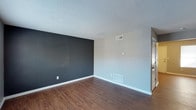 This two-floor space offers a well-thought-out layout with a clean, modern aesthetic throughout. The interior is characterized by rich, warm hardwood-style flooring that runs seamlessly across the living areas, adding a sense of warmth and continuity to the space. Walls are finished in a neutral light gray palette, complemented by striking dark charcoal accent walls that create visual depth and a contemporary focal point in select rooms. Ceilings feature a classic textured finish, adding subtle character overhead. HVAC vents are positioned both on the walls and floors, ensuring efficient climate control throughout each level. White baseboards provide a crisp contrast against both the flooring and wall colors, contributing to a tidy, polished look. The open, uncluttered nature of the rooms allows for flexible furniture arrangements and personalization. Overall, the space presents a practical yet stylish environment with a neutral color scheme that serves as a versatile backdrop, making it easy to adapt to a variety of interior styles and preferences across both floors.